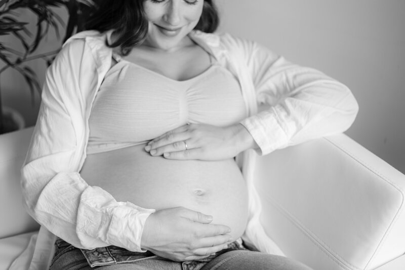 NH Maternity Photographer Kathleen Jablonski captures young mother looking at her pregnant belly during maternity session