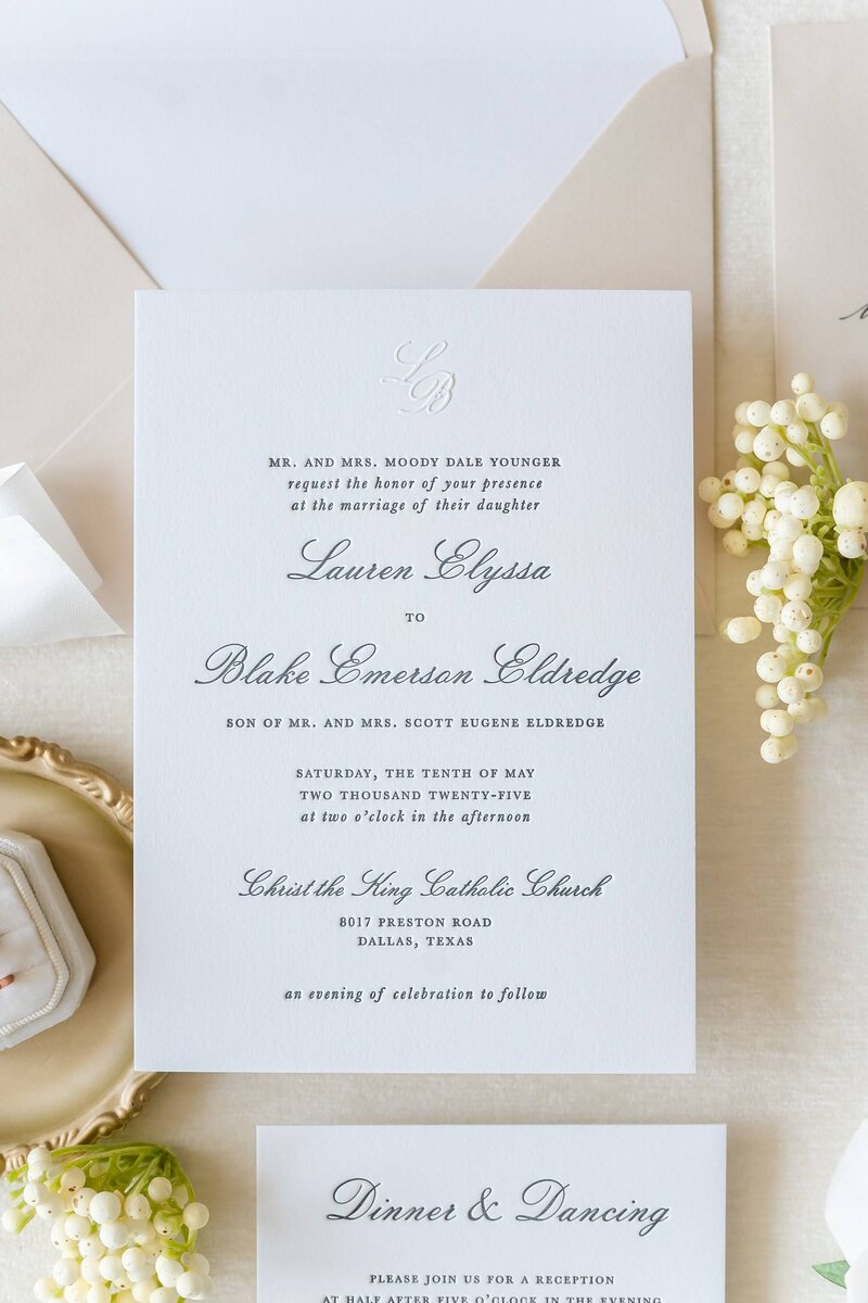 Classic black and white letterpress wedding invitation with a blind pressed monogram and tan envelope