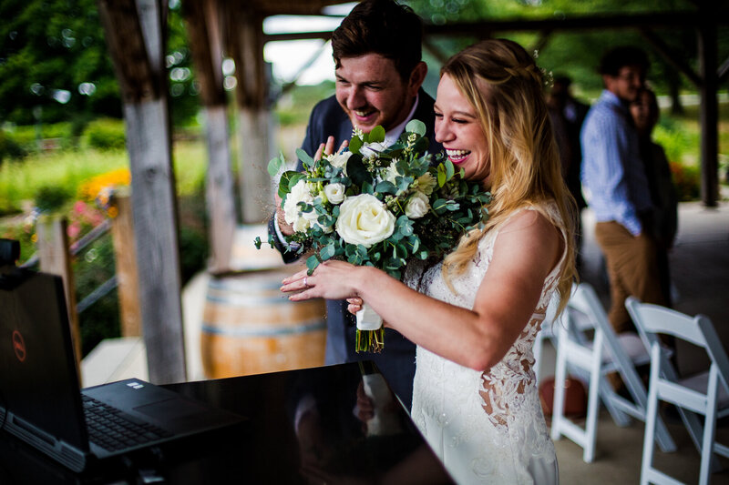 Bride and groom show off rings to their virtual guests at the end of their Quincy cellars wedding ceremony