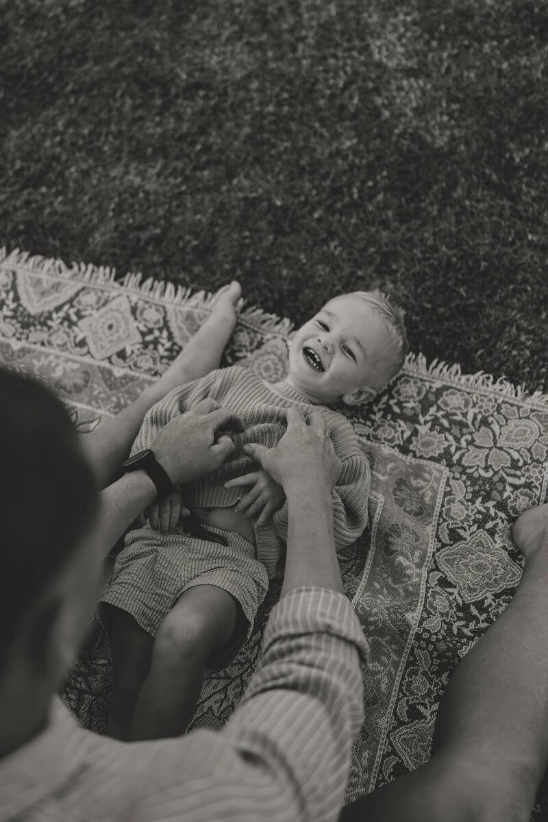 Child laughing while being tickled during a candid family photoshoot.