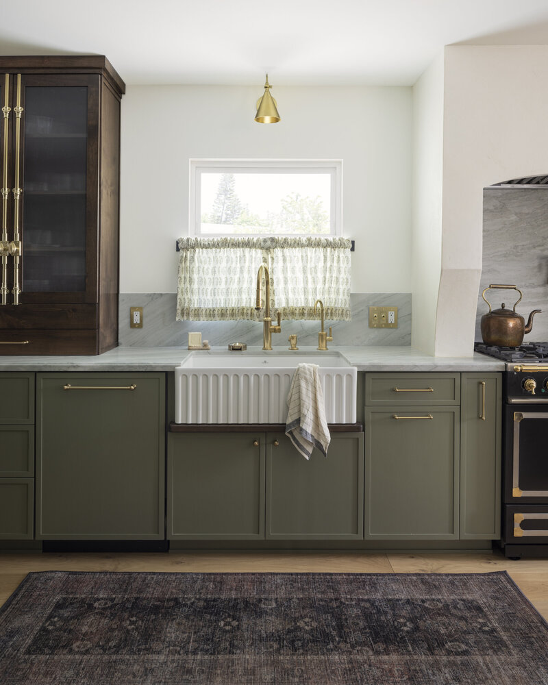 White fluted kitchen sink with  stained drip rail. Quartzite countertops with brass switch plates and brass electrical plates.