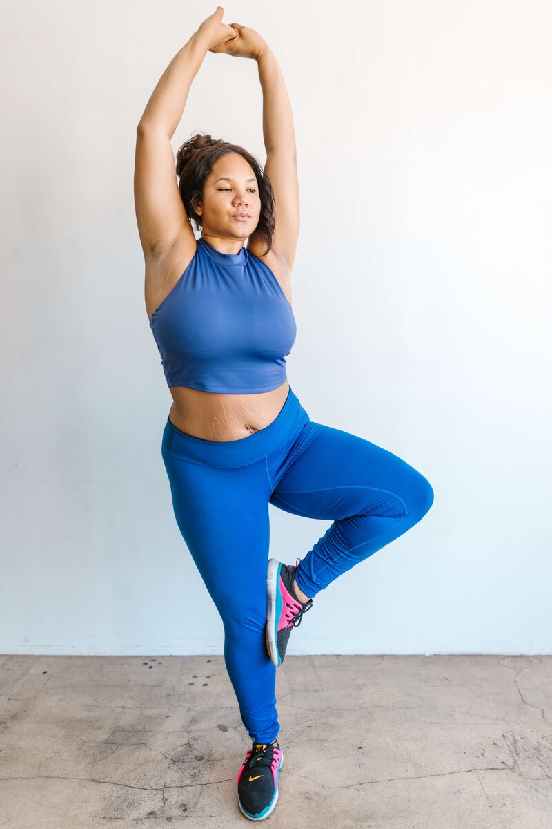 Woman in blue stretching upwards