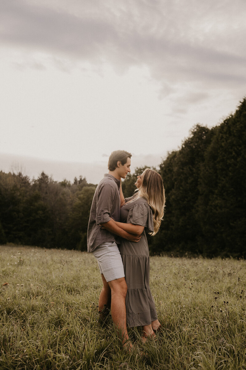 engaged couple posed in grassy meadow