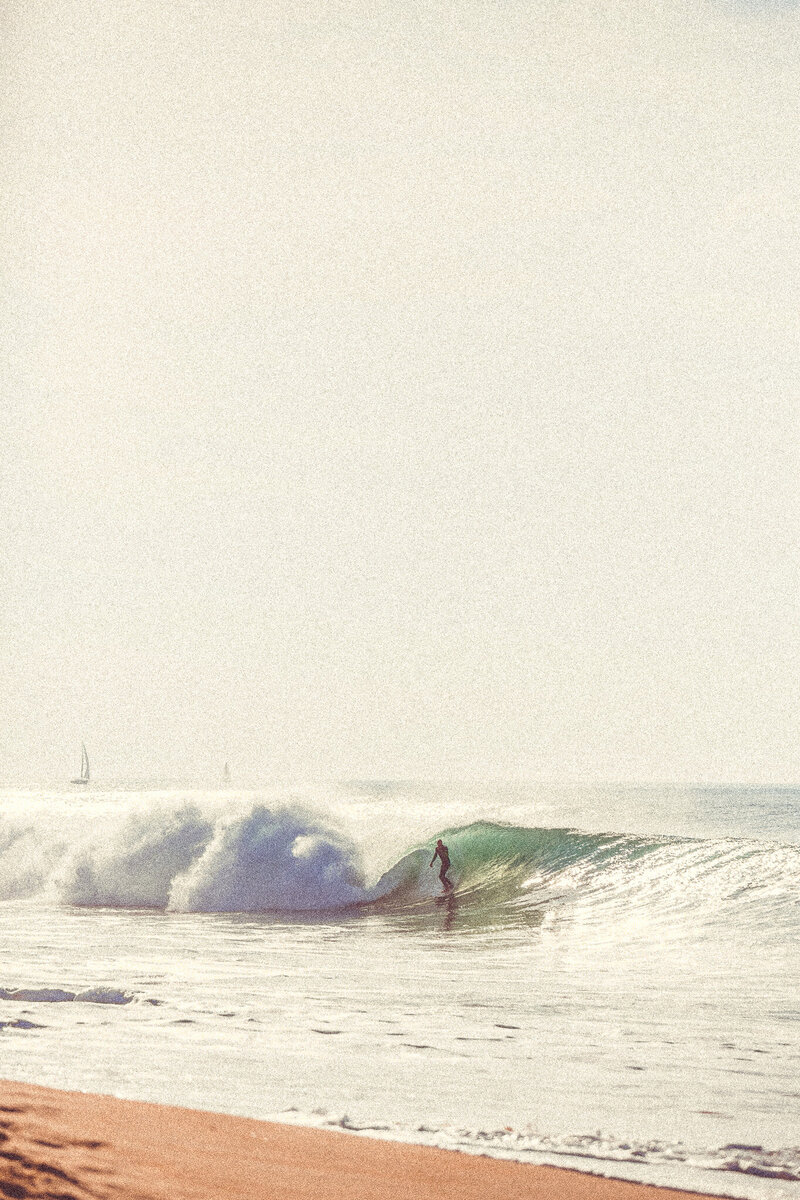 hazy beach with large wave and a surfer
