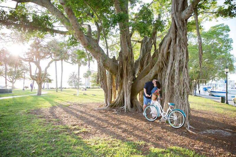 engaged couple kissing under a banyan tree at Bayfront Park in downtown Sarasota