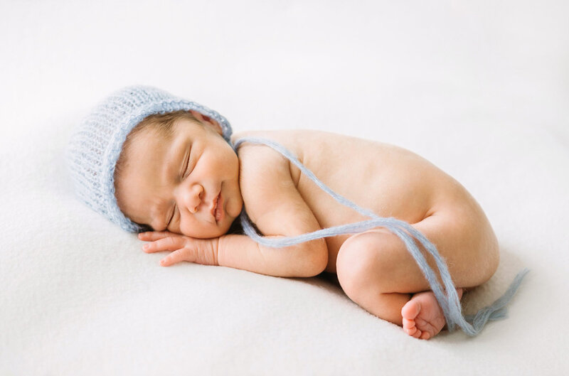 A newborn baby in a delicate light blue knit bonnet