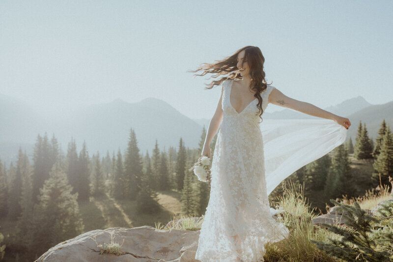 Brides hair blows in the wind as she twirls in her wedding dress on top of a mountain in Ouray, Colorado