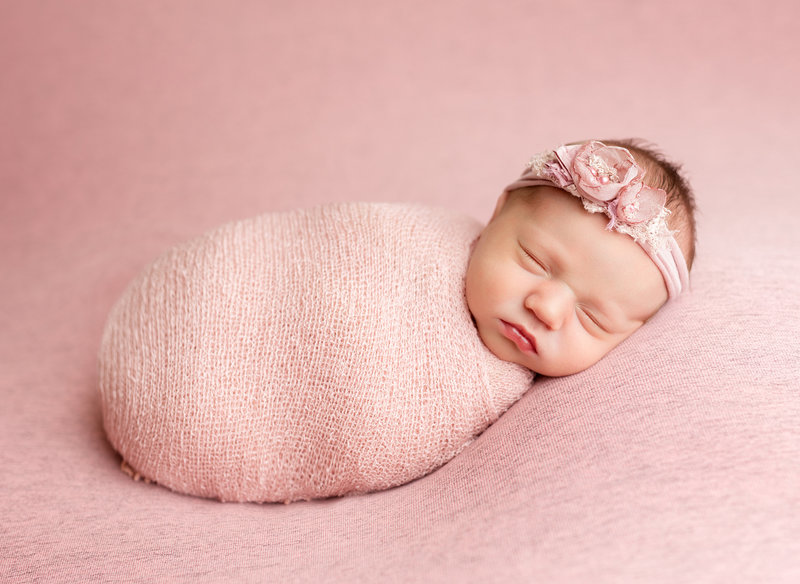 Baby wrapped in dusty rose colored blanket