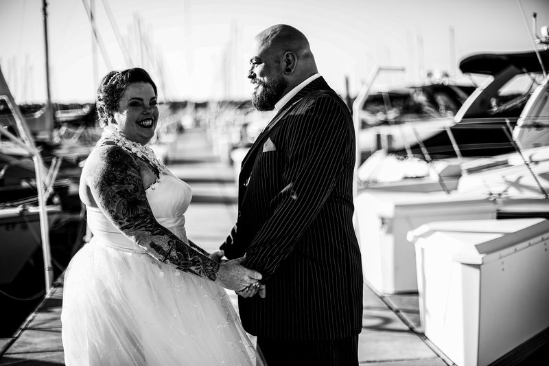 Bride and groom hold hands next to some boats at the Erie Yacht Club