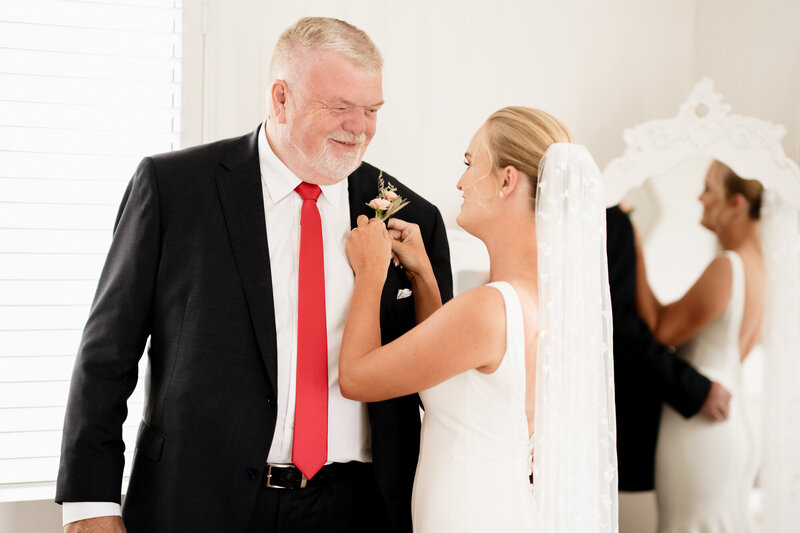 A bride puts a flower on dad