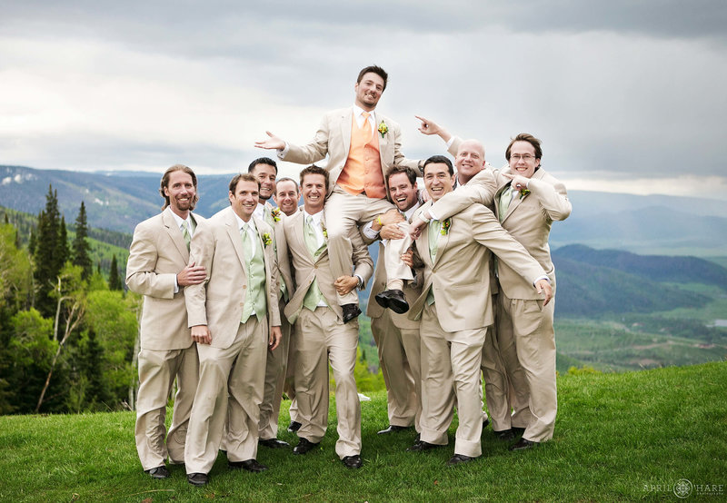 A groom is lifted up onto his groomsmen's shoulders at his wedding on Thunderhead Lawn next to Thunderhead Lodge in Steamboat Springs Colorado