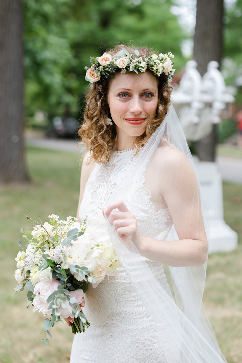 bride smirking at camera while holding her wedding veil
