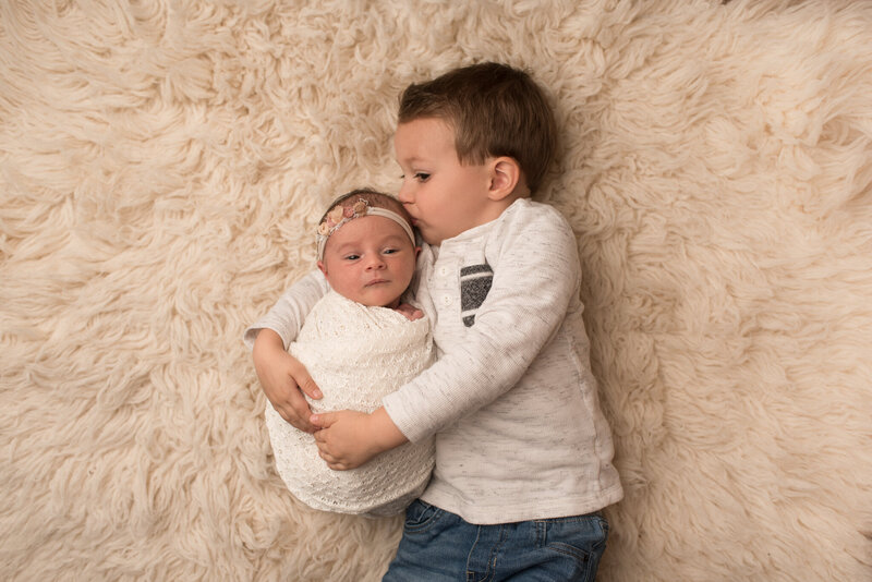 Little brother kissing baby sister at newborn session