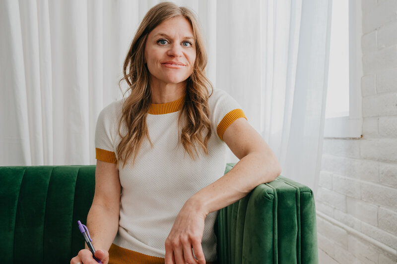 Beth Requist, custom web designer, sitting on green couch with notepad and pen