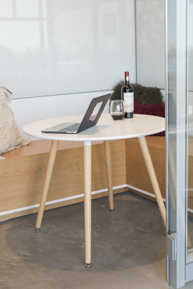 a laptop, glass of wine, and bottle of wine sitting on a table
