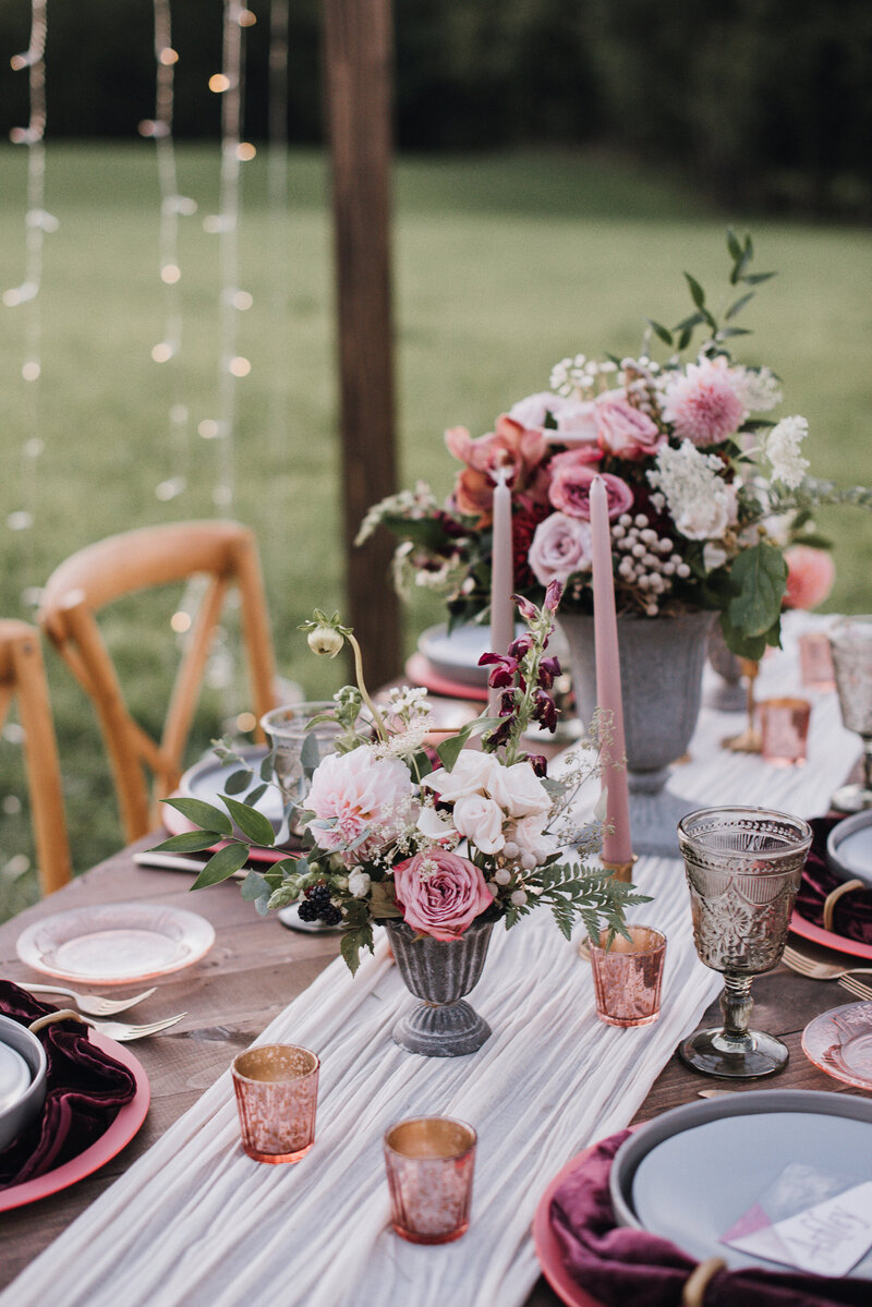 An outdoor wedding reception table with a blush, burgundy white and gray decor theme.