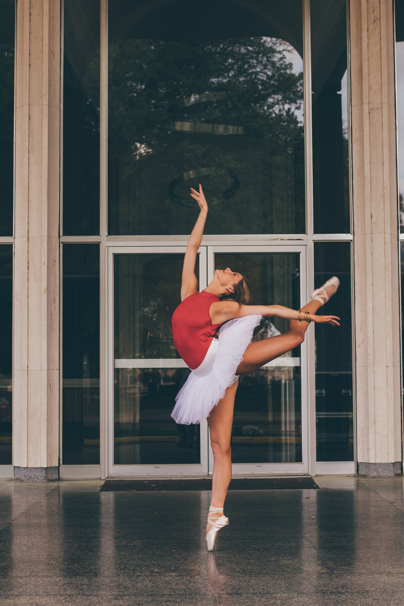 A ballet dancer performing gracefully in front of a beautiful building.