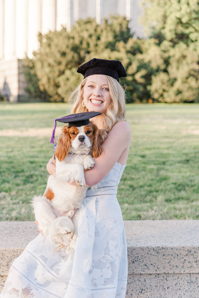 girl wearing matching graduation cap with her dog during senior photos in Washington, DC