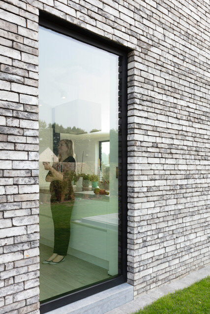 architect staat in haar keuken, te zien van achter de glaspartij. woning te keerbergen