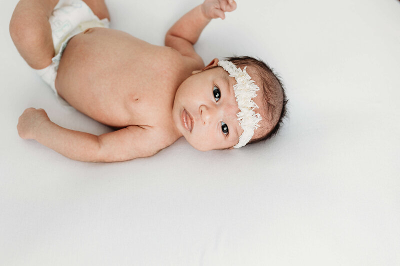 Newborn baby girl stretched out and posing during newborn session