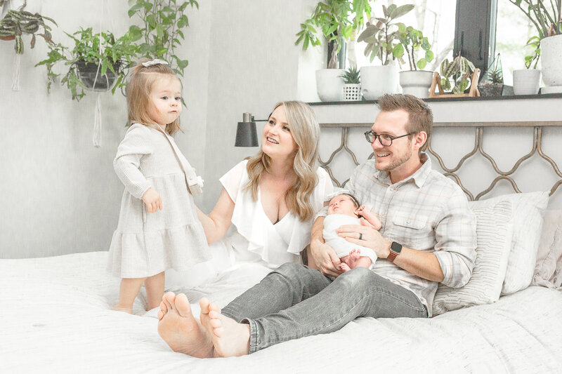 Family on bed celebrating new baby with lifestyle photography session taken by Ann Arbor Newborn Photographer