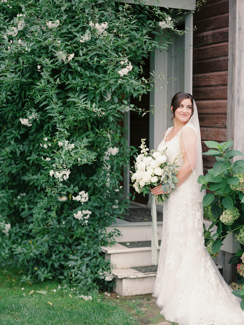 bride holding wedding bouquet and looking off over her shoulder and smiling