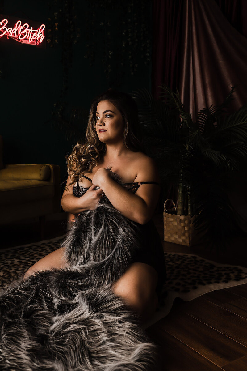 boudoir photo shoot client holding fur rug looking away