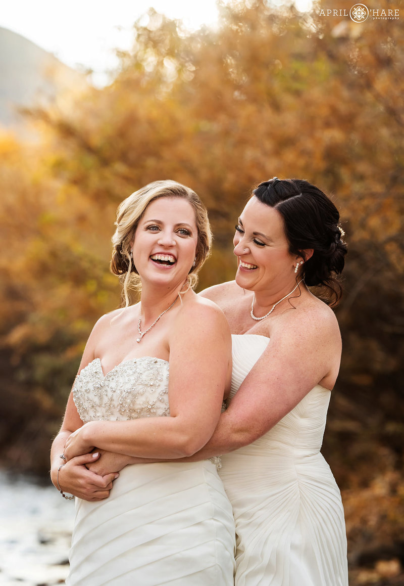 Brides laugh together on their same sex wedding day on a pretty autumn day at the Golden Hotel
