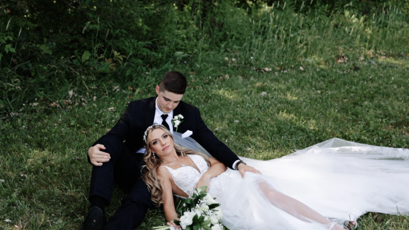 bride laying in the grooms lap in a grassy field