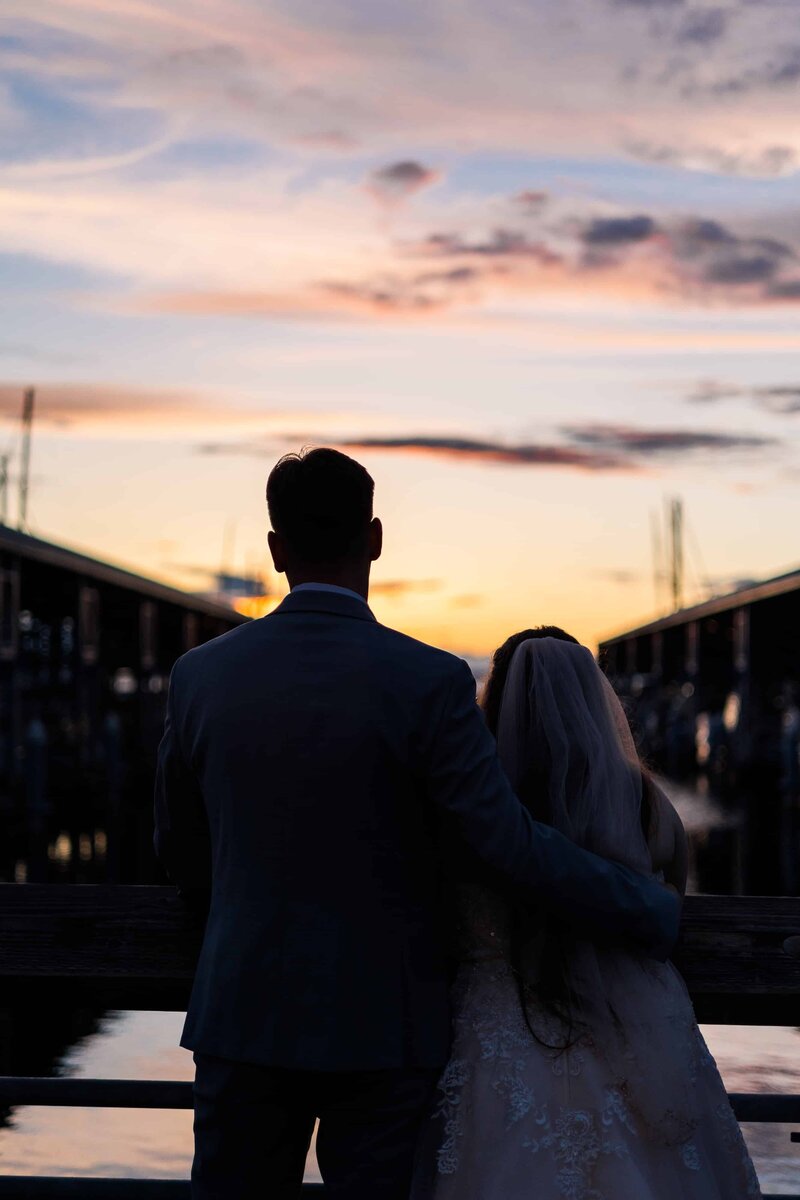 Couple looking off into bright sunset off of Edmond's Yacht Club