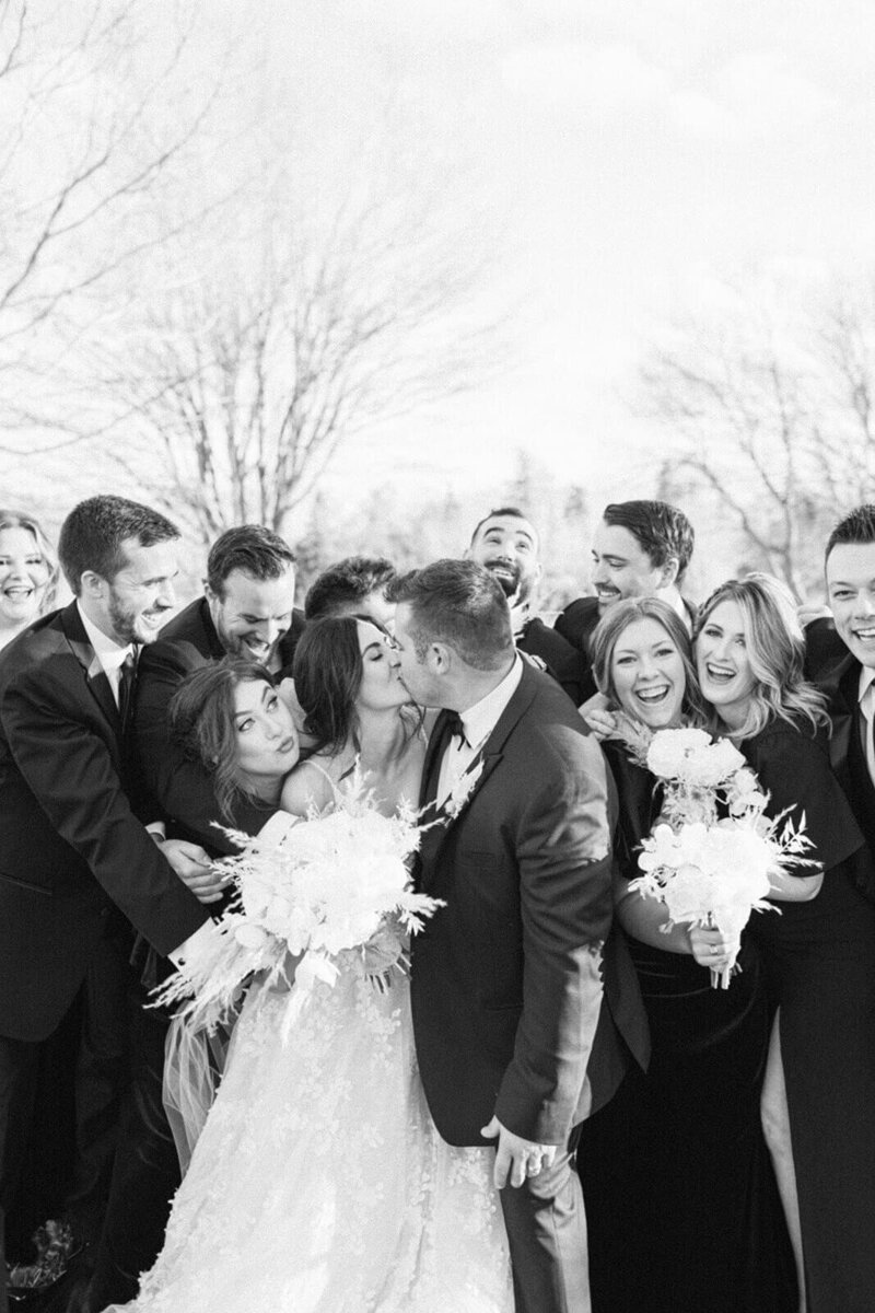 groom-and-bride-kiss-infront-of-wedding-party