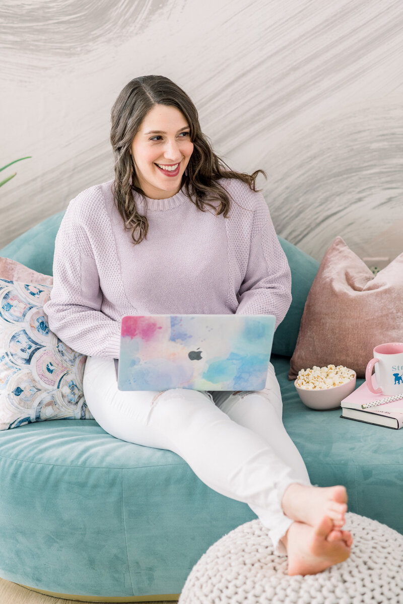 Isabel Kateman sitting on a blue couch designing a website with the laptop on her lap