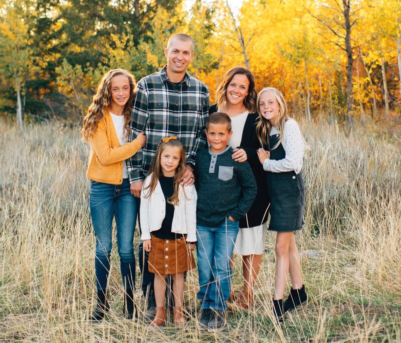 dustin hulme of elk ridge builders poses with his wife, two daughters and their horse