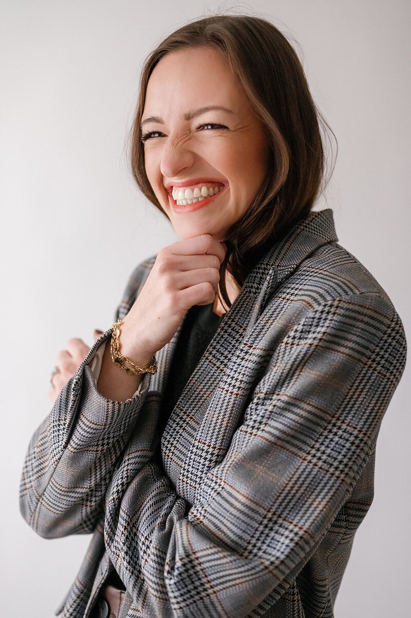 Woman in a plaid blazer smiling and looking to the side
