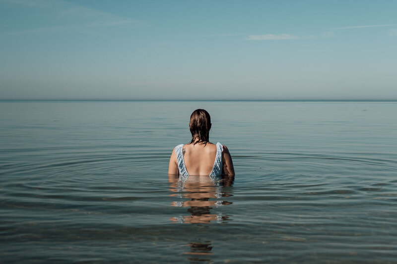 Woman sitting in the ocean watching the horizon
