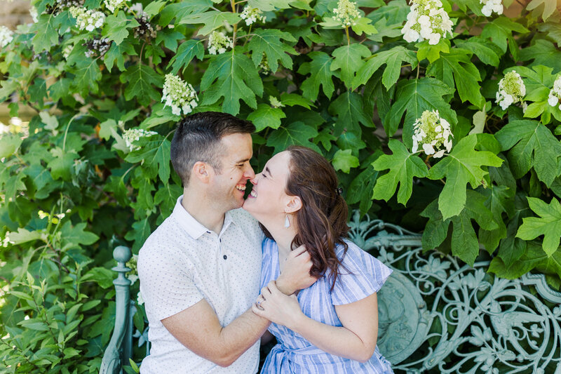 Summer engagement session on a bench with peonies in the background.