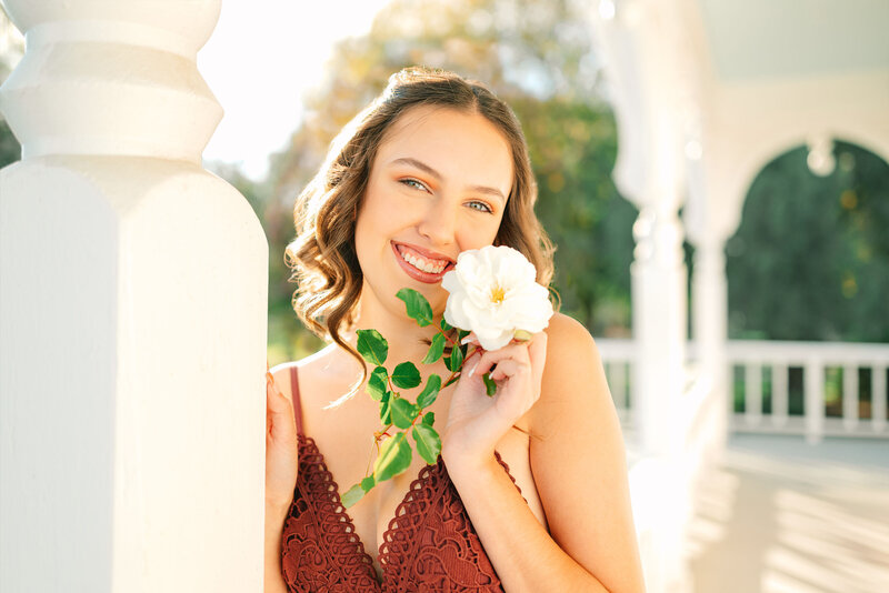 High school senior girl portrait on a front porch with a white rose