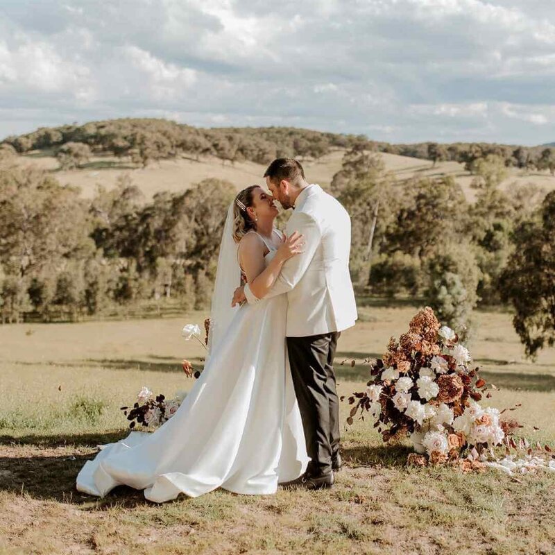 Bride and groom kissing on hill