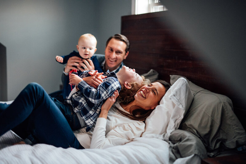 family with two sons laying on bed