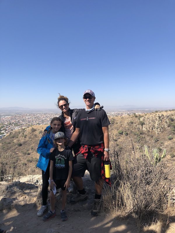 EnForma co-founders Errin and Alicia enjoying a family hike with their children on a scenic trail at the Jardín Botánico, overlooking San Miguel De Allende—reflecting the brand’s values of wellness, nature, and community.