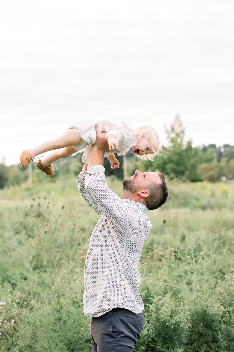 Father lifting his toddler daughter into the air at a family session