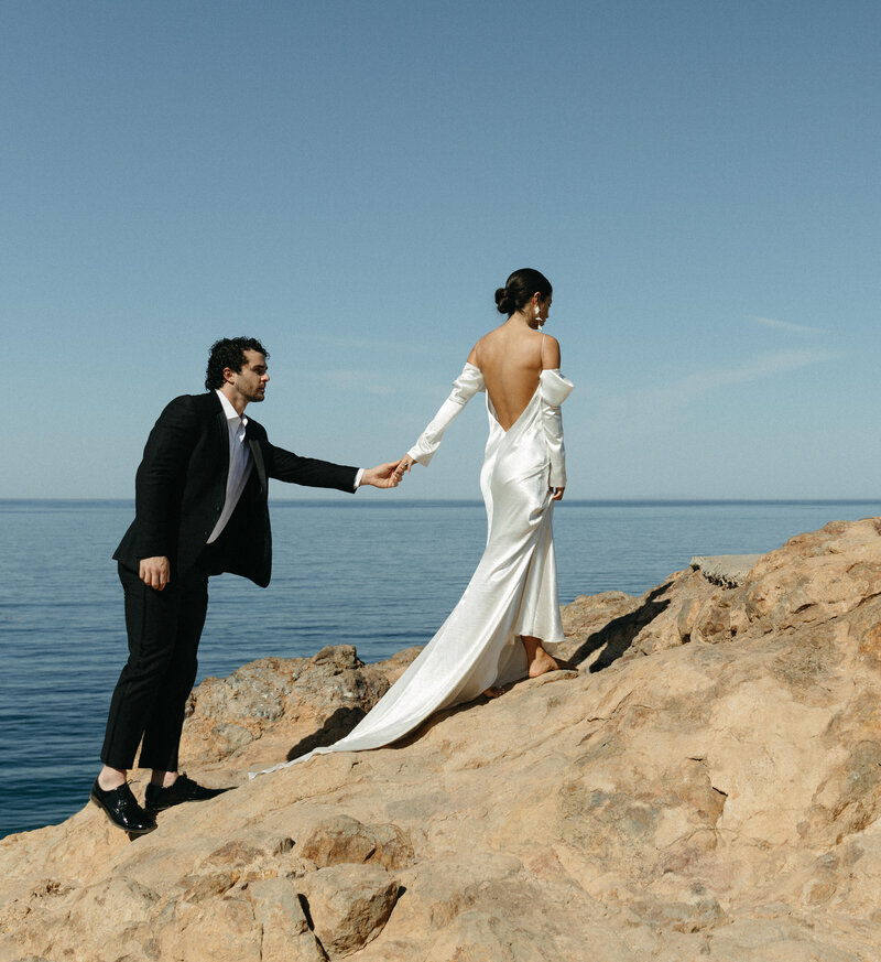 bride and groom walking by the ocean on cliffs