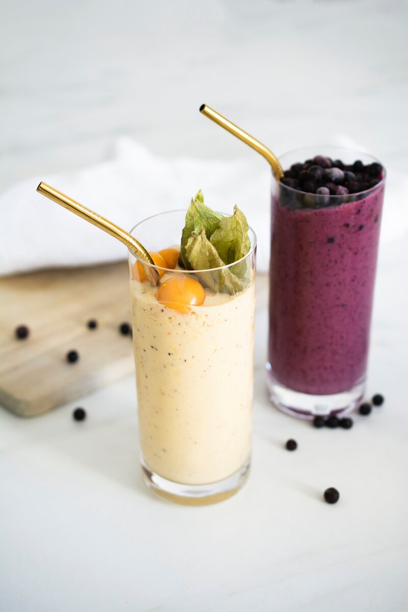 Nourishing smoothies with fruit on top and gold metal straws