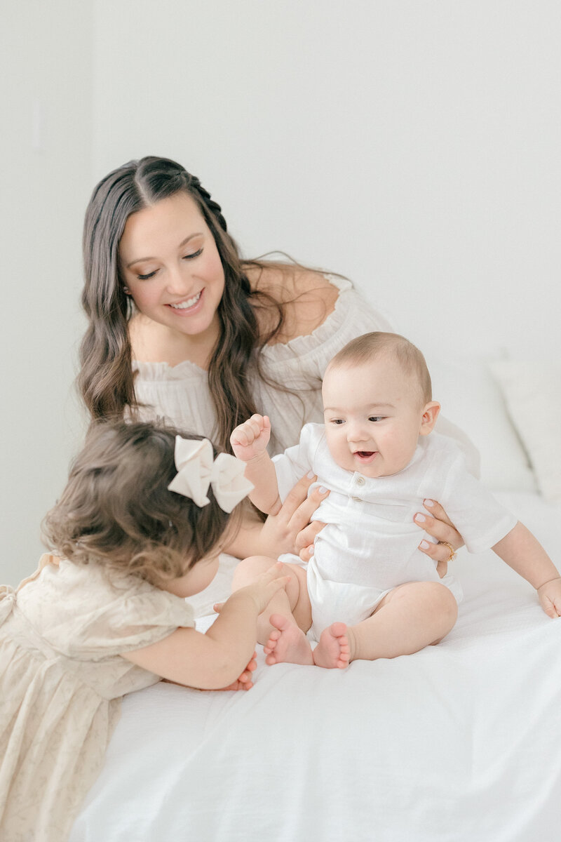 A mom with her two young children having a tickle fight in all white studio in NJ by a NJ photographer