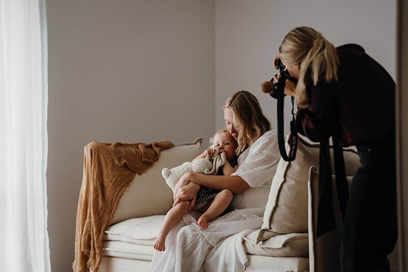 A behind the scenes image of new plymouth photographer aimee kelly while she photographs a mother and baby