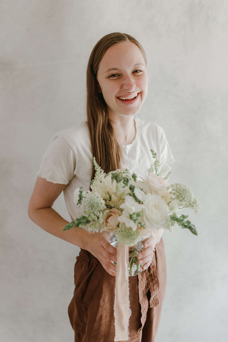 woman holding bouquet of flowers and smiling at camera