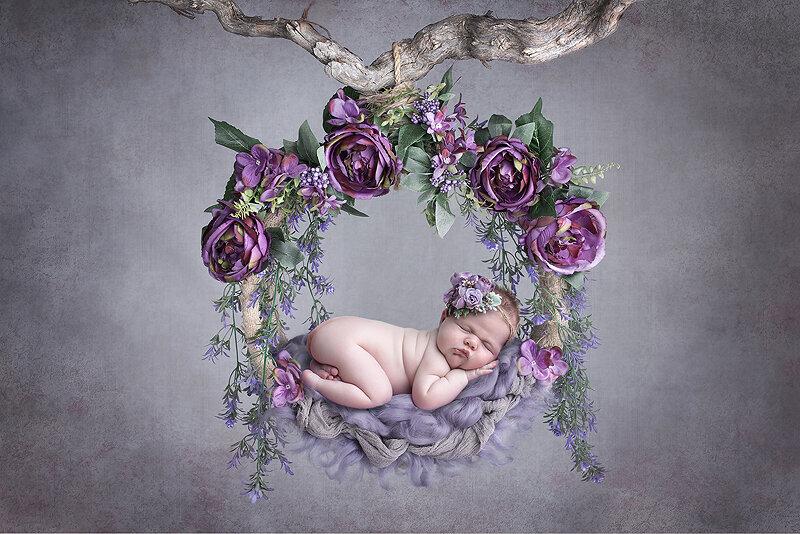Newborn girl on purple swing