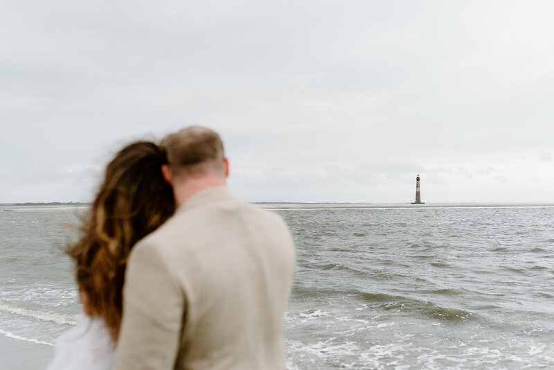 elopement couple at folly beach looking at lighthouse