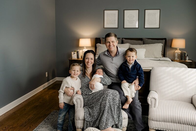 Family of five in a Charlotte Area home lifestyle newborn session where Mom is holding the newborn and each of their older children is sitting beside mom and dad