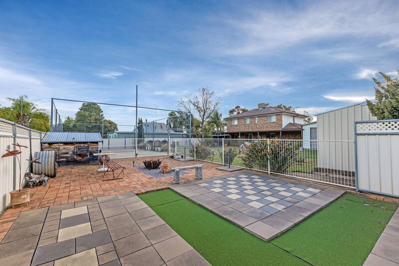 Back exterior of a single-storey cottage-style home with a wraparound porch and well-kept front lawn.